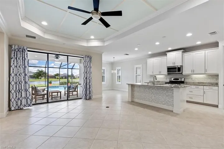 Kitchen with white cabinets, stainless steel appliances, crown molding, ceiling fan, and sink