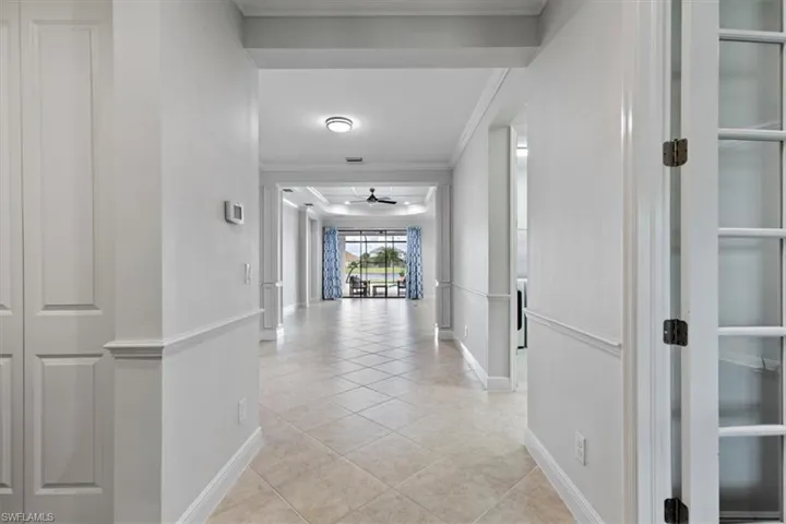 Hallway featuring light tile patterned flooring and crown molding