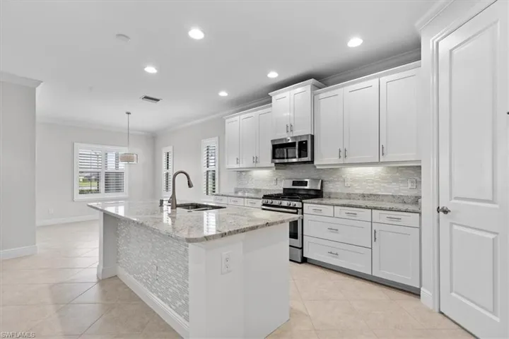 Kitchen with appliances with stainless steel finishes, crown molding, sink, and white cabinetry