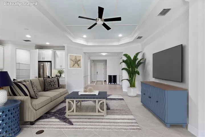 Living room featuring ceiling fan, light tile patterned floors, a tray ceiling, and ornamental molding