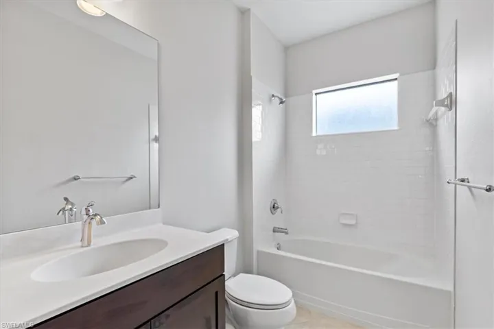 Full bathroom with tile patterned flooring, tiled shower / bath, vanity, and toilet