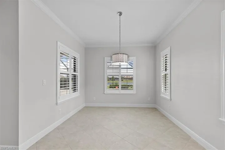 Unfurnished dining area with light tile patterned flooring and crown molding