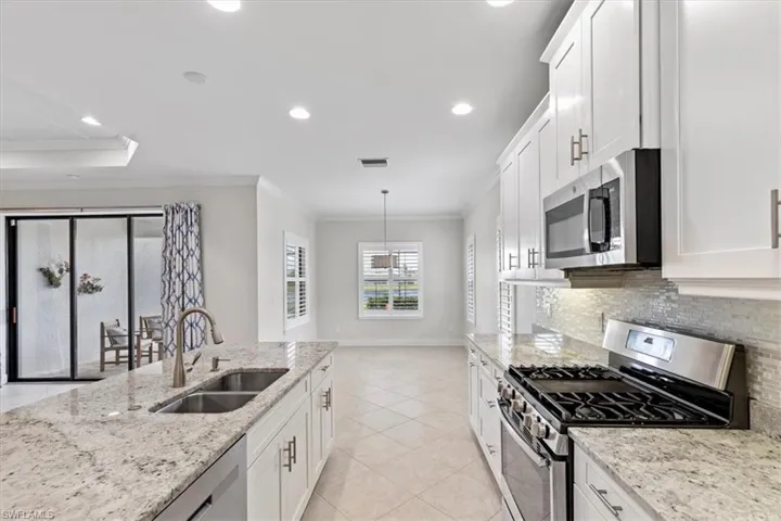 Kitchen featuring white cabinets, pendant lighting, sink, tasteful backsplash, and appliances with stainless steel finishes