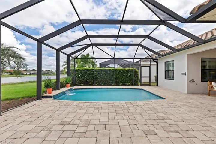 View of pool with a patio, a water view, and glass enclosure
