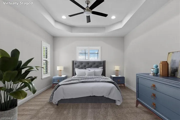 Bedroom with carpet floors, a raised ceiling, and ceiling fan