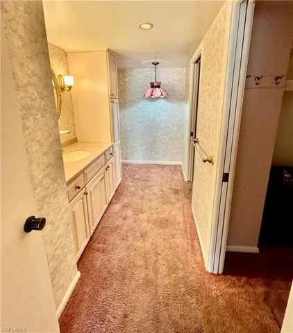 Hallway with light carpet and sink