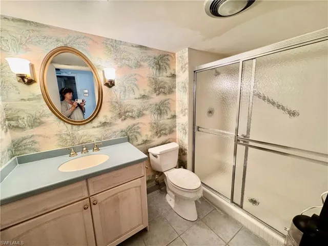 Bathroom with tile patterned floors, vanity, toilet, and a shower with shower door
