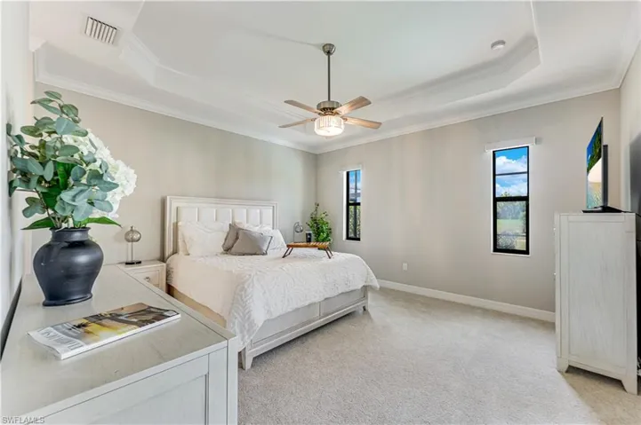 Spacious bedroom featuring a tray ceiling, recessed lighting, and a ceiling fan