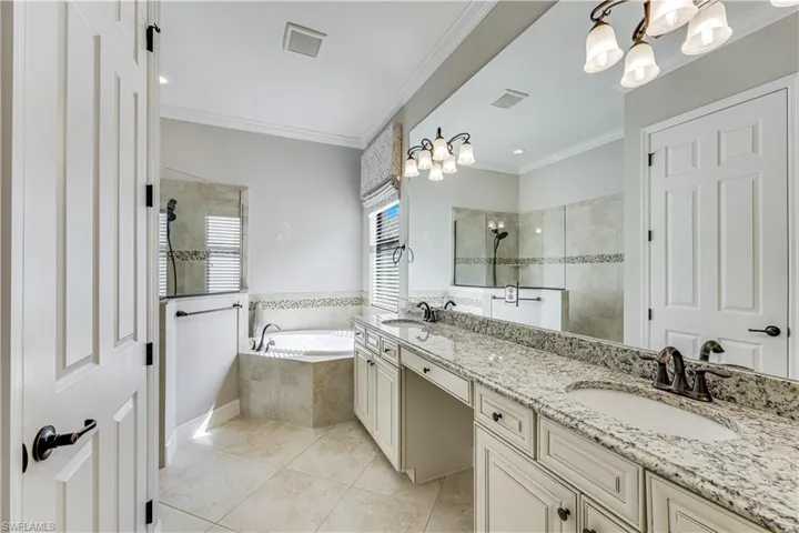 Bathroom featuring a double vanity with granite countertop, integrated sinks, and bronze-finish fixtures