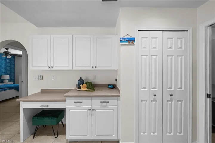 Kitchen featuring white cabinets, arched walkways, light countertops, and light tile patterned flooring