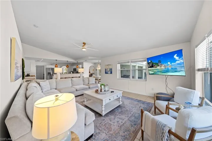 Living room with vaulted ceiling, a ceiling fan, and tile patterned floors