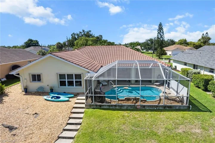 Back of house with stucco siding, a sunroom, glass enclosure, an outdoor pool, and a tile roof