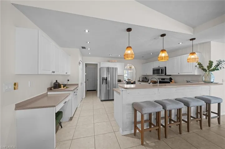 Kitchen with a breakfast bar area, white cabinets, stainless steel appliances, and recessed lighting