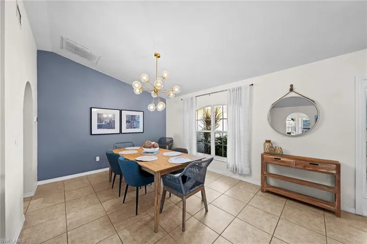 Dining area featuring vaulted ceiling, arched walkways, light tile patterned floors, and a chandelier