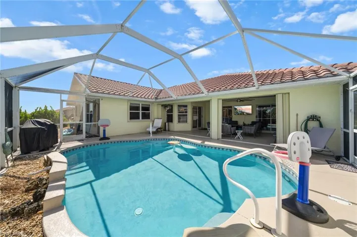 Swimming pool with a sunroom, a patio area, ceiling fan, and a grill