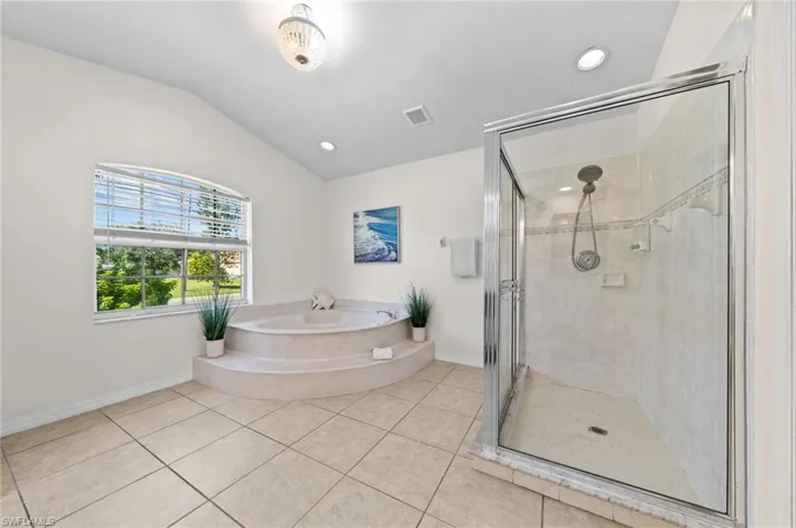 Full bathroom featuring a stall shower, light tile patterned flooring, a bath, lofted ceiling, and recessed lighting
