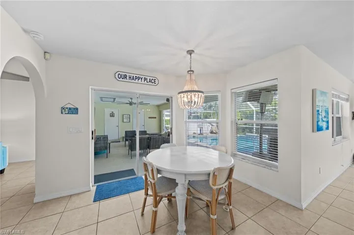 Dining area with ceiling fan, light tile patterned floors, a chandelier, and arched walkways