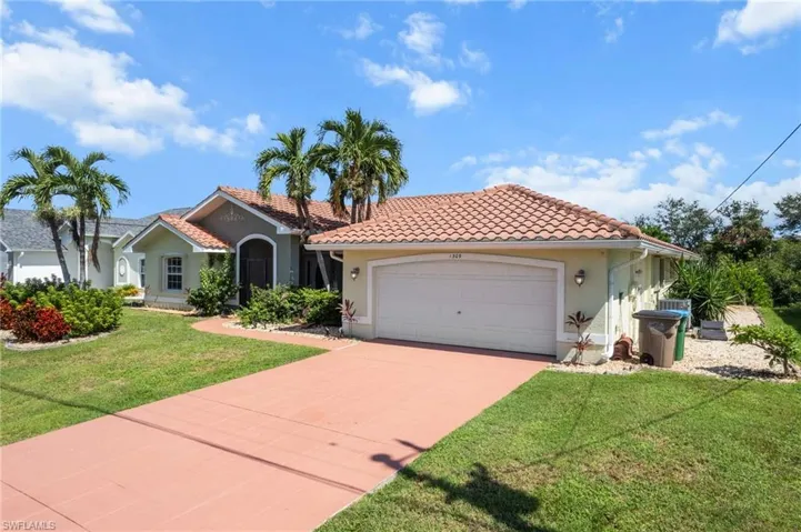 Mediterranean / spanish-style home featuring a garage, driveway, stucco siding, a front yard, and a tile roof