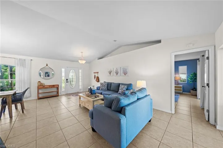 Living area featuring light tile patterned floors, vaulted ceiling, and healthy amount of natural light