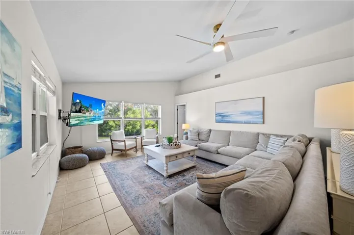 Living area featuring lofted ceiling, light tile patterned floors, and ceiling fan