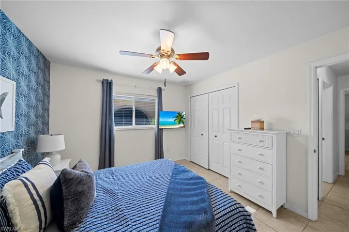 Bedroom with light tile patterned floors, ceiling fan, a closet, and wallpapered walls