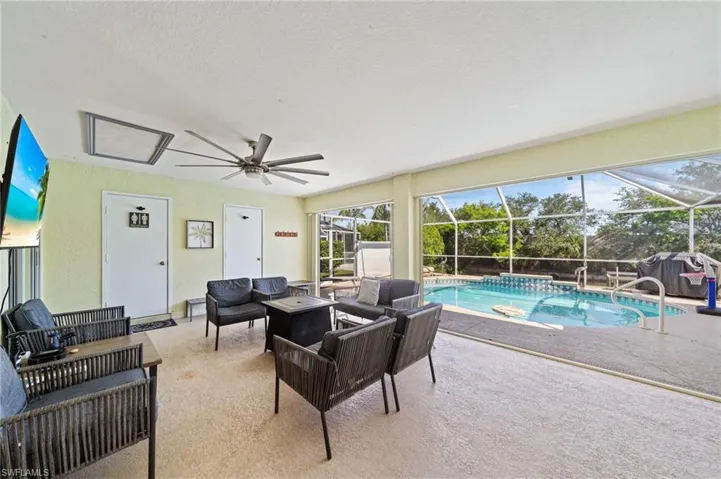 Living room with a sunroom, carpet floors, a ceiling fan, and a textured ceiling