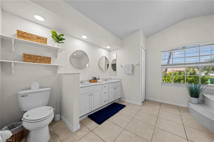 Bathroom featuring double vanity, light tile patterned flooring, a garden tub, and recessed lighting