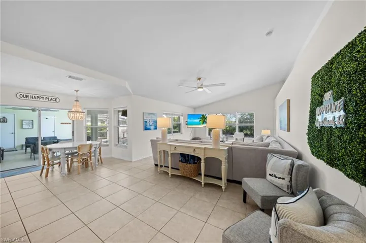 Living area featuring light tile patterned flooring, lofted ceiling, and a ceiling fan