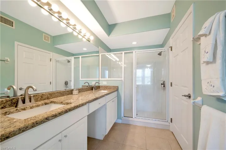 Primary Bathroom with double vanity, a stall shower, and light tile patterned floors