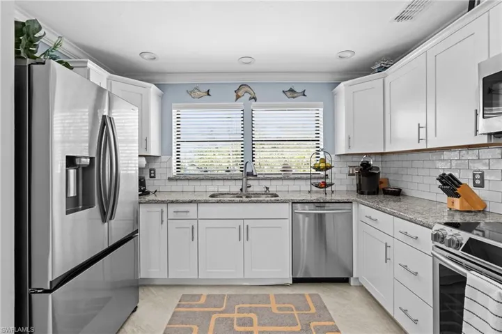 Kitchen featuring white cabinets, a sink, crown molding, and appliances with stainless steel finishes