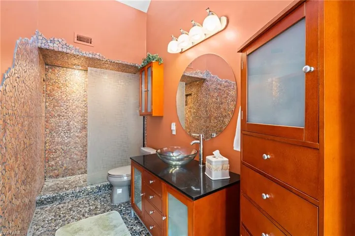 Bathroom featuring visible vents, toilet, a tile shower, and vanity