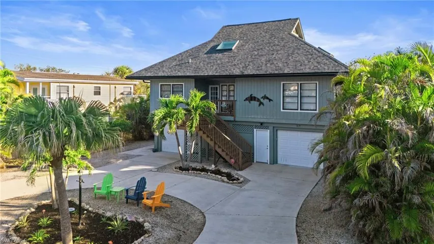 View of front of home featuring driveway, a shingled roof, a garage, and stairs