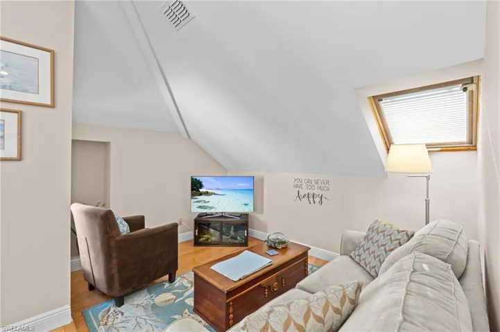 Living room with baseboards, visible vents, vaulted ceiling, and wood finished floors