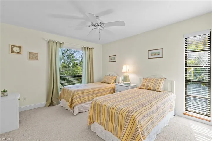 Bedroom featuring light colored carpet, baseboards, and a ceiling fan