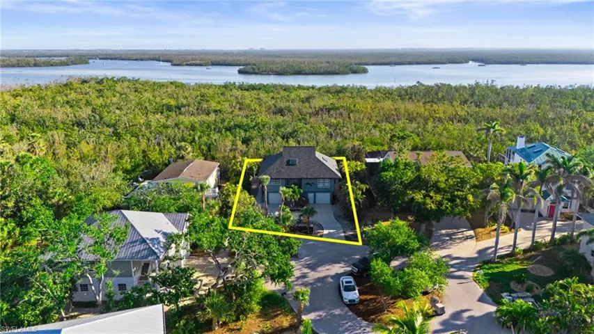 Drone / aerial view with a water view and a view of trees virtually enhanced