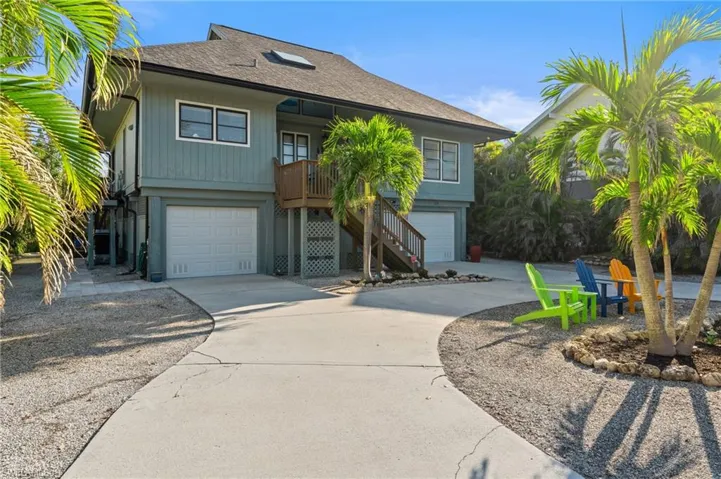 Coastal inspired home featuring roof with shingles, driveway, stairs, and an attached garage