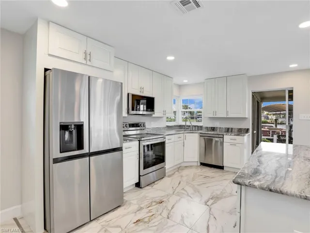 Kitchen featuring a water view, recessed lighting, and marble finish floors