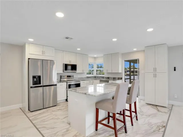 Kitchen featuring a water view, recessed lighting, and marble finish floors