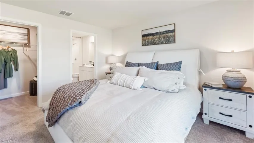 Model home. Bedroom featuring light colored carpet, a closet, and ensuite bathroom