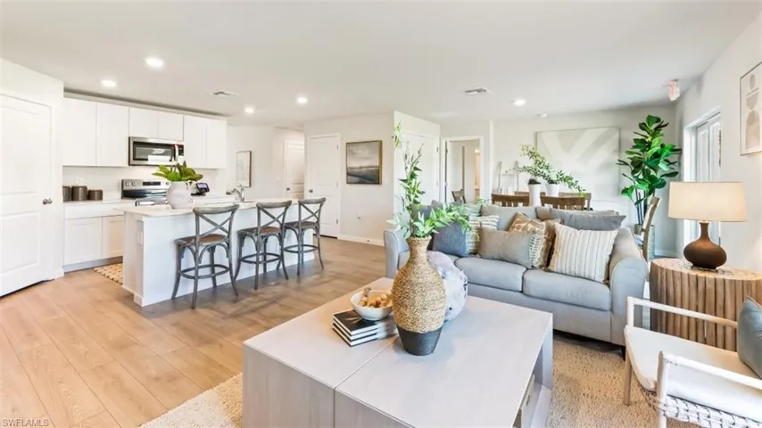 Model home. Living area with light wood-style floors and recessed lighting