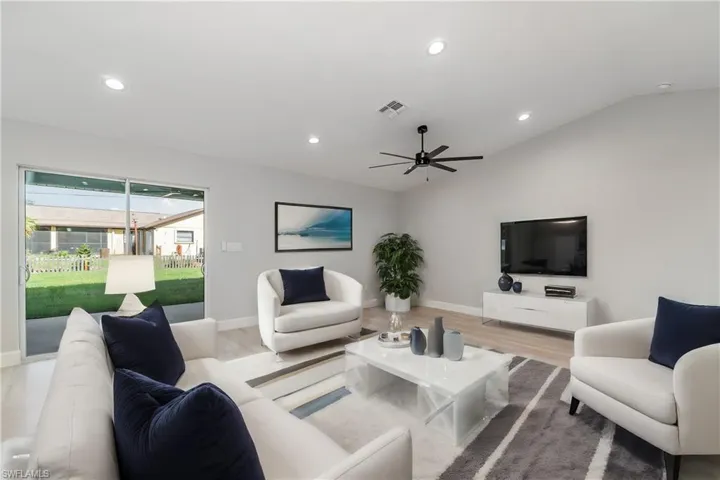 Living room featuring ceiling fan, light hardwood / wood-style flooring, and lofted ceiling
