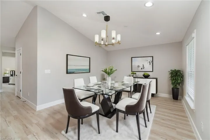 Dining area with lofted ceiling, light hardwood / wood-style flooring, and an inviting chandelier