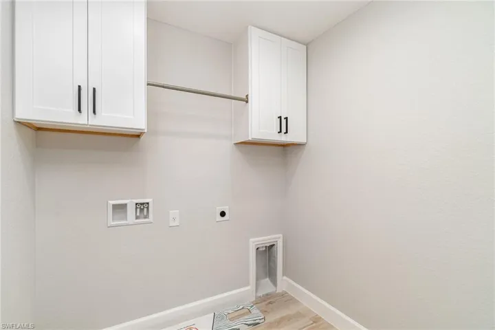Laundry room featuring hookup for a washing machine, light hardwood / wood-style flooring, cabinets, and hookup for an electric dryer