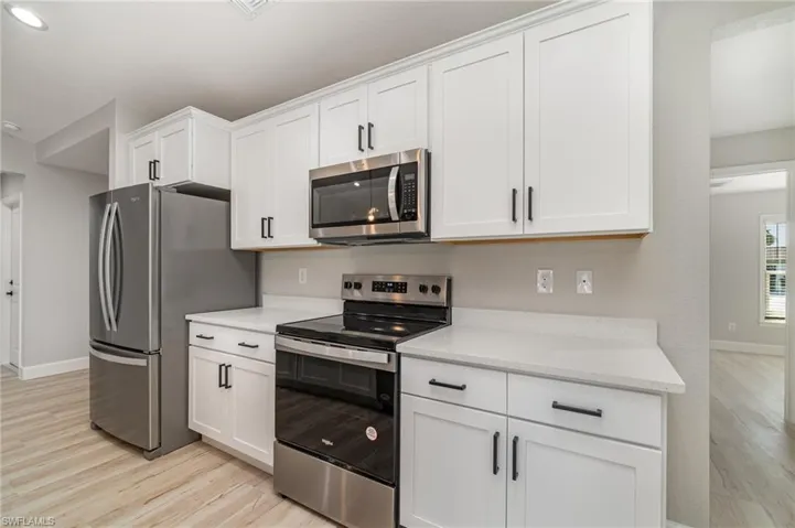Kitchen featuring light hardwood / wood-style floors, appliances with stainless steel finishes, and white cabinets