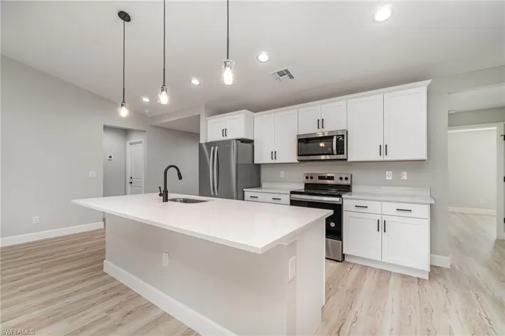 Kitchen with light hardwood / wood-style floors, sink, an island with sink, and stainless steel appliances