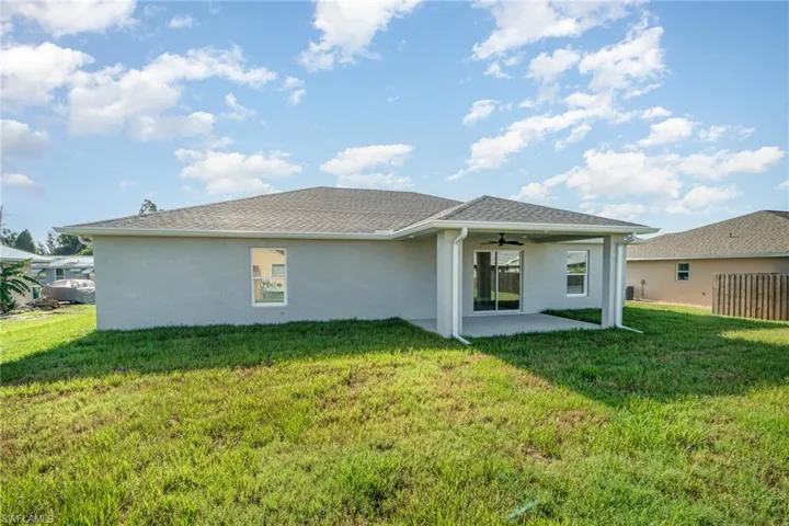 Rear view of property featuring a patio, a yard, and ceiling fan