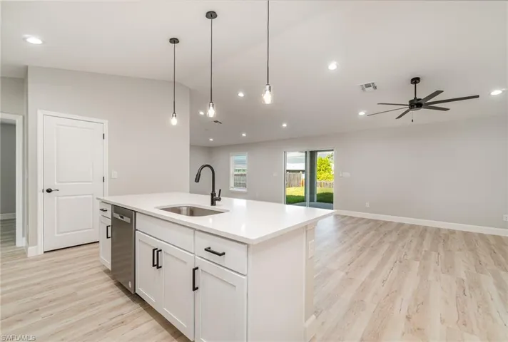 Kitchen with ceiling fan, white cabinets, an island with sink, sink, and light hardwood / wood-style floors