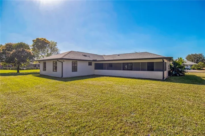 Rear view of house featuring a sunroom and a yard