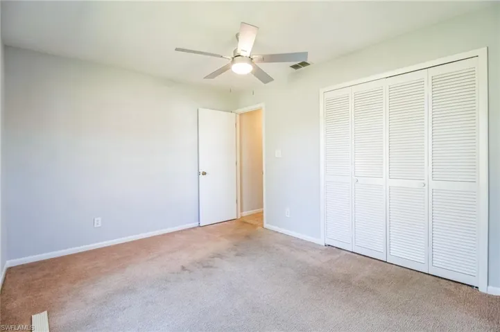 Unfurnished bedroom featuring ceiling fan, a closet, and light colored carpet