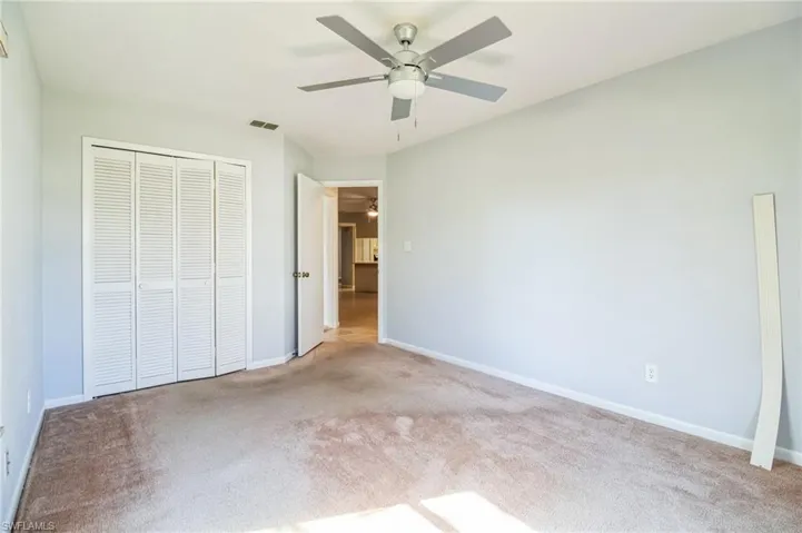 Unfurnished bedroom featuring ceiling fan, light carpet, and a closet